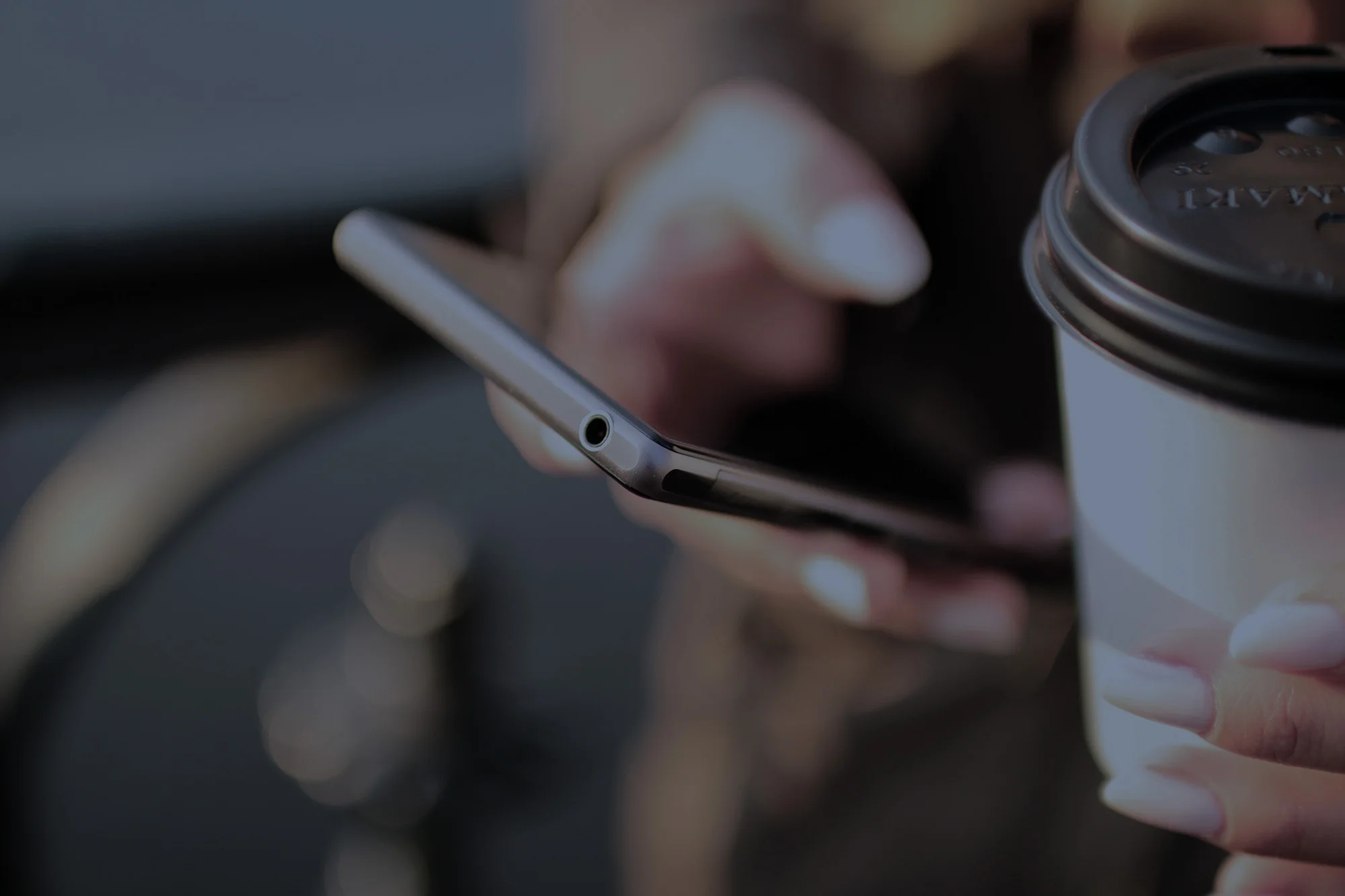 Persona con smartphone e caffè da asporto